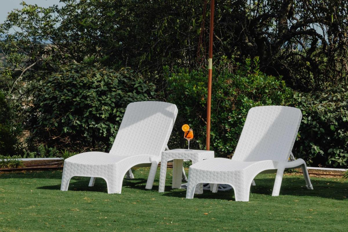 três cadeiras brancas sentadas na grama com uma flor de laranjeira em Hotel Rural Quinta do Marco - Nature & Dining em Tavira