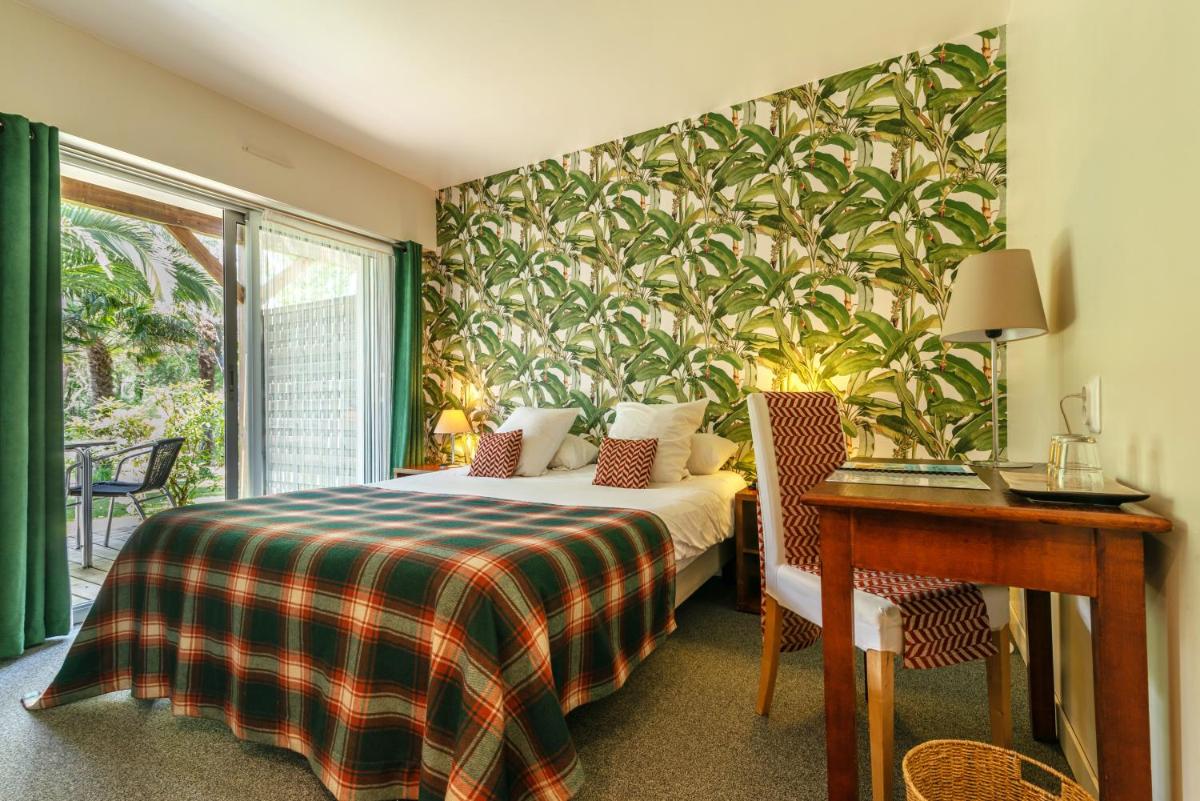 - une chambre avec un lit, un bureau et un mur orné de plantes dans l'établissement Carnac Lodge Hotel & Spa, à Plouharnel