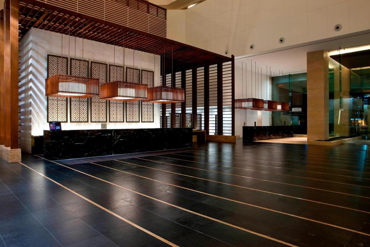 a lobby with a black floor and chandeliers at The Westin Hyderabad Mindspace in Hyderabad