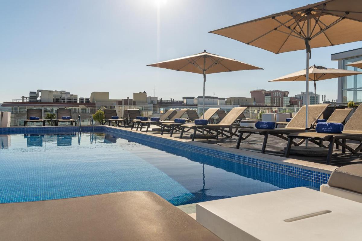 uma piscina com cadeiras e guarda-sóis em um prédio em Jupiter Lisboa Hotel - Rooftop & Spa em Lisboa