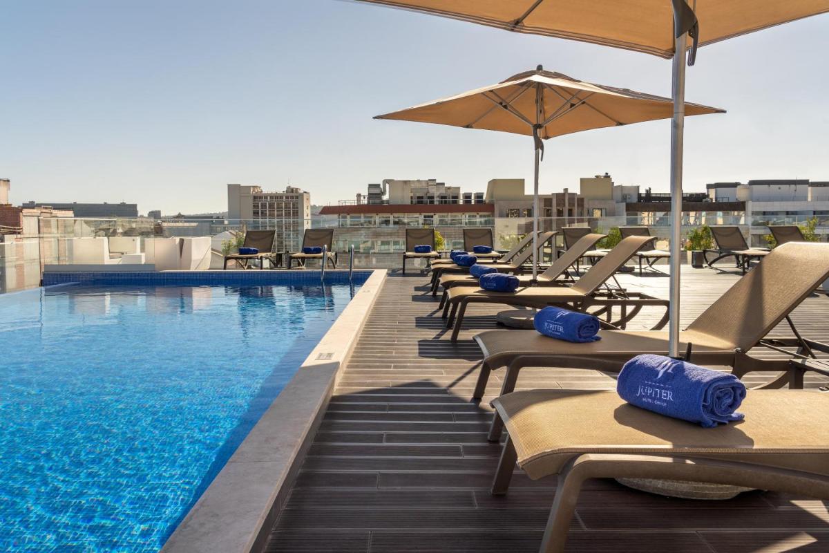 uma piscina com cadeiras e guarda-sóis em um terraço em Jupiter Lisboa Hotel - Rooftop & Spa em Lisboa