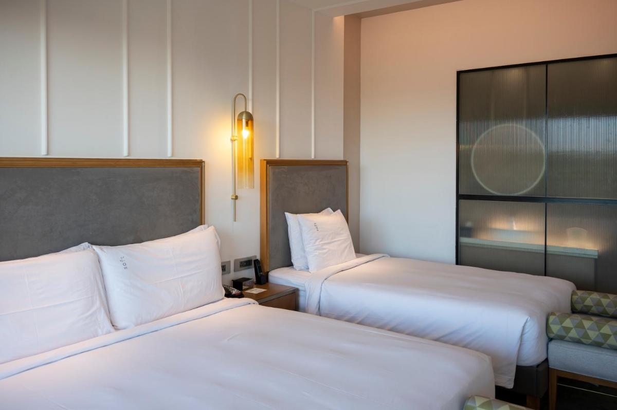 two beds in a hotel room with white sheets at Holiday Inn Goa Candolim in Candolim two beds in a hotel room with white sheets at Holiday Inn Goa Candolim in Candolim