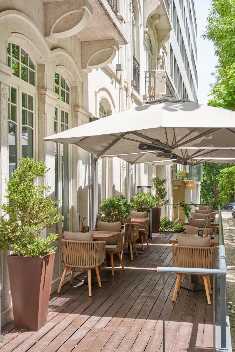 um pátio com mesas, cadeiras e um guarda-sol em PortoBay Liberdade em Lisboa