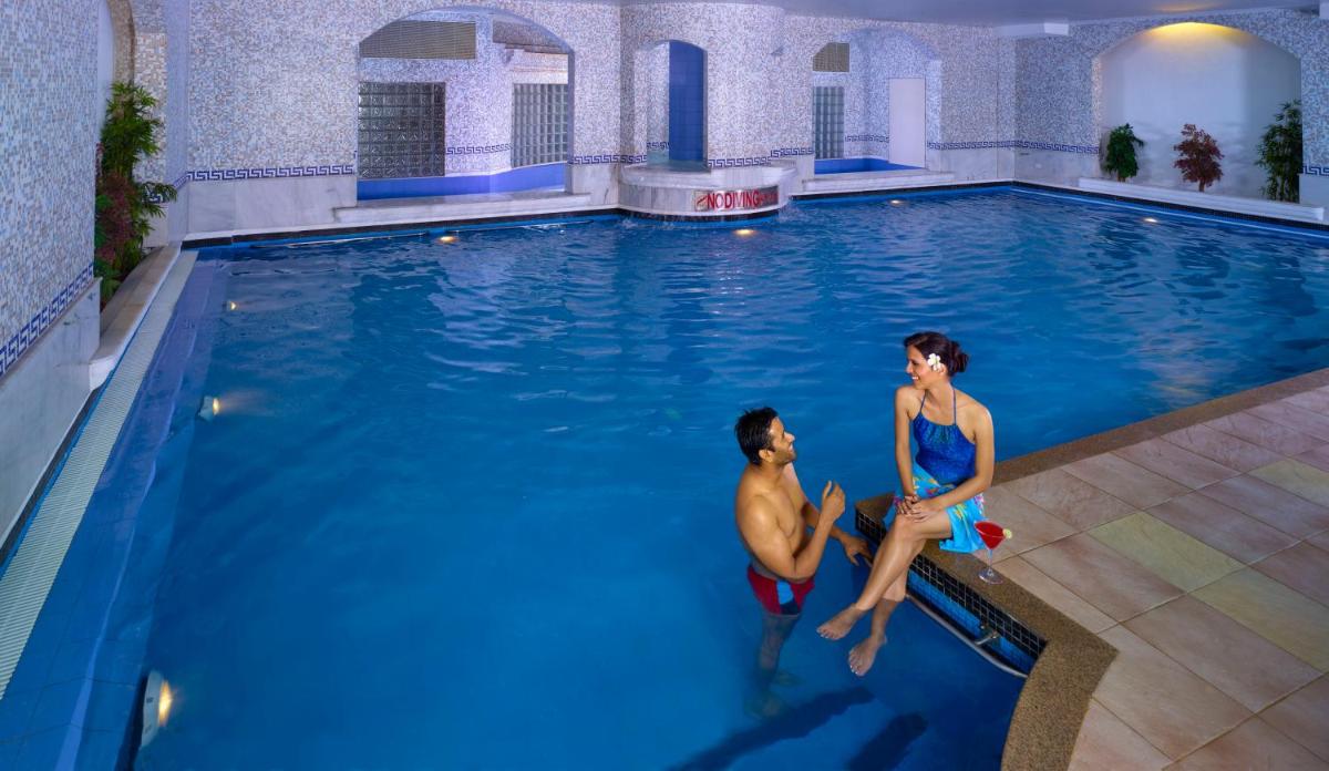a man and a woman sitting in a swimming pool at Grand Chennai by GRT Hotels in Chennai