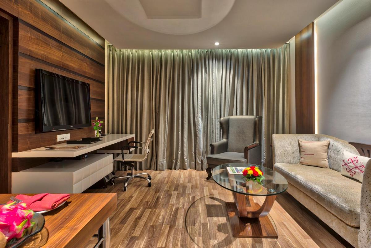 a living room with a couch and a table and a desk at Grand Chennai by GRT Hotels in Chennai