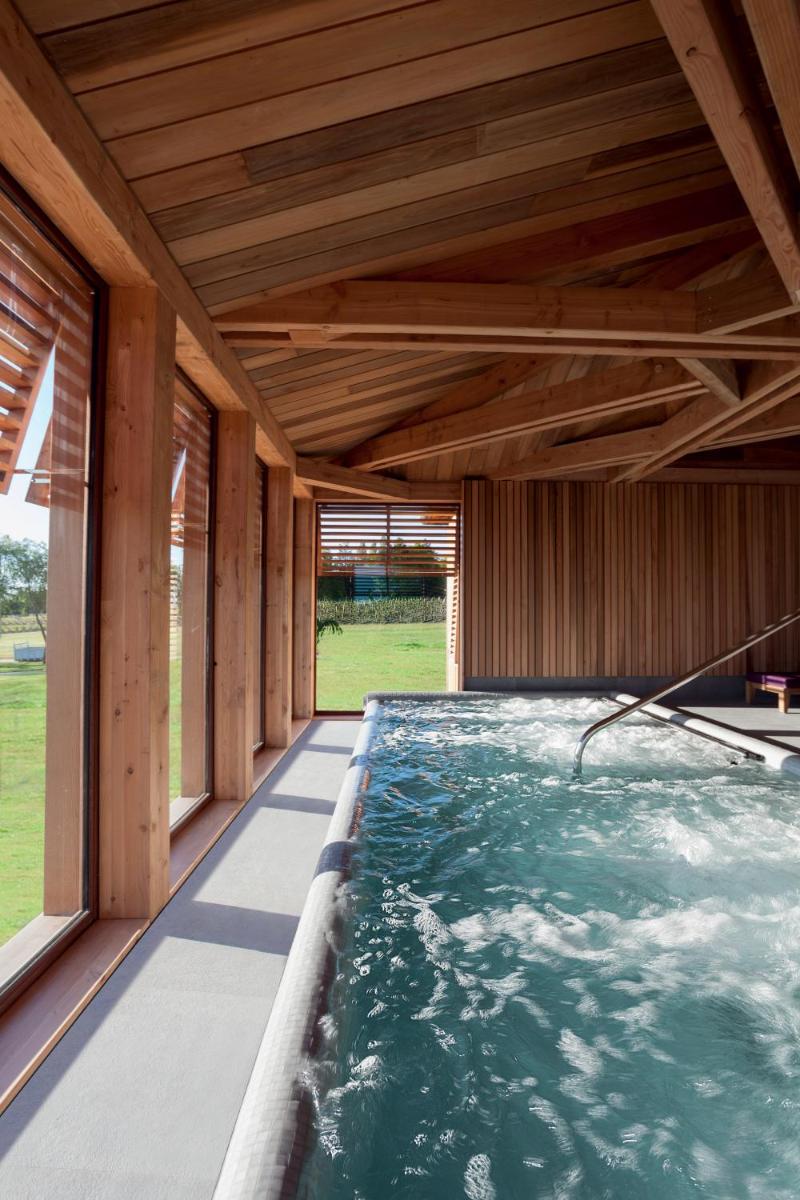 un jacuzzi intérieur dans une maison en bois avec des fenêtres dans l'établissement Les Sources de Caudalie, à Martillac