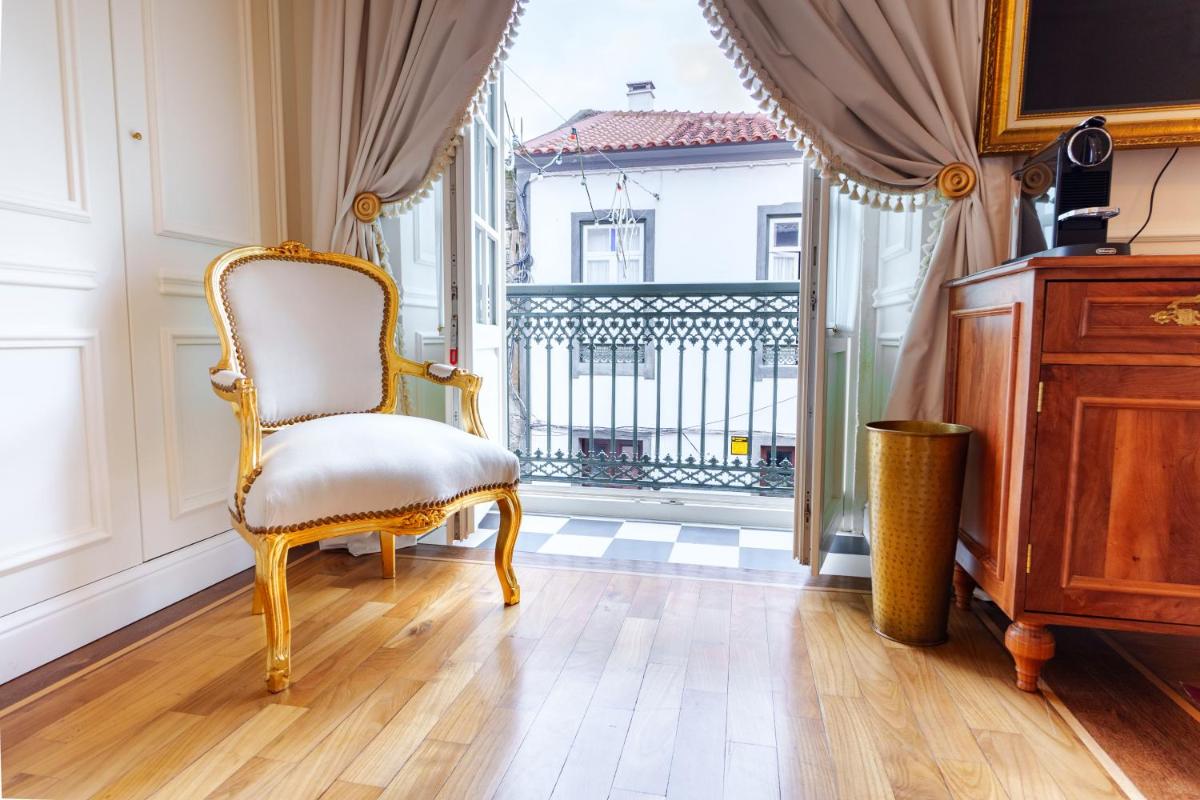 uma cadeira sentada em uma sala com janela em Boutique Hotel Teatro em Angra do Heroísmo