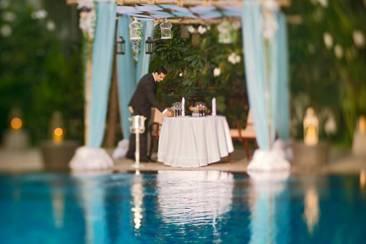 a man sitting at a table next to a pool at Taj Coromandel in Chennai