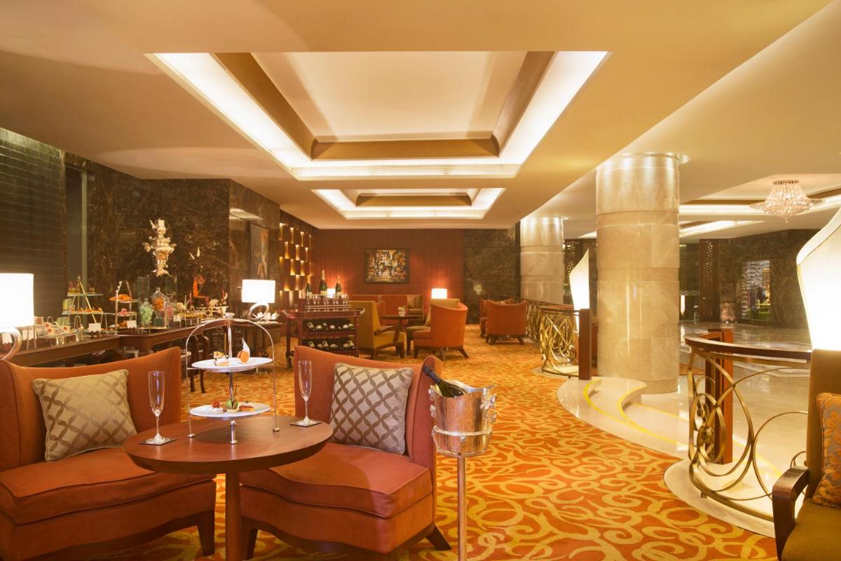 a hotel lobby with tables and chairs and a bar at Taj Coromandel in Chennai