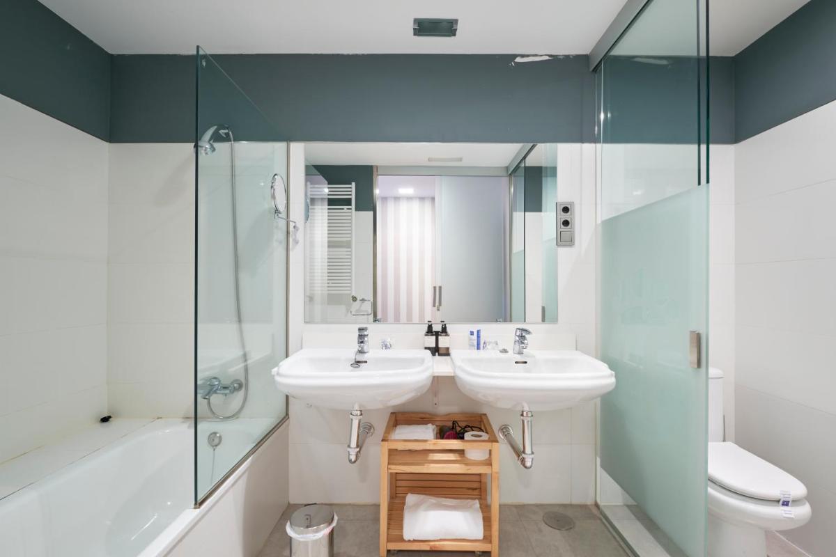 Un baño con dos lavabos y una ducha. en Hotel AR Isabel de Farnesio, en La Granja de San Ildefonso