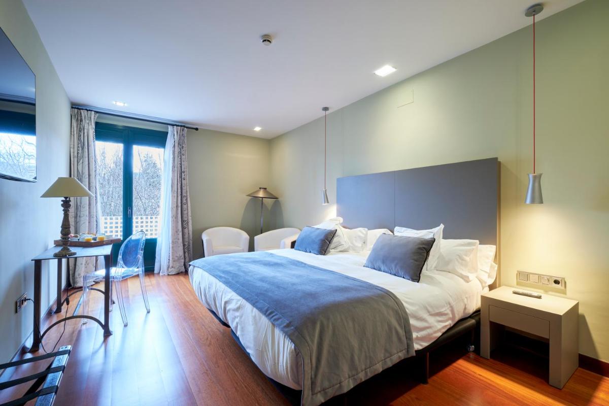 Un dormitorio con una cama grande con una manta azul. en Hotel AR Isabel de Farnesio, en La Granja de San Ildefonso