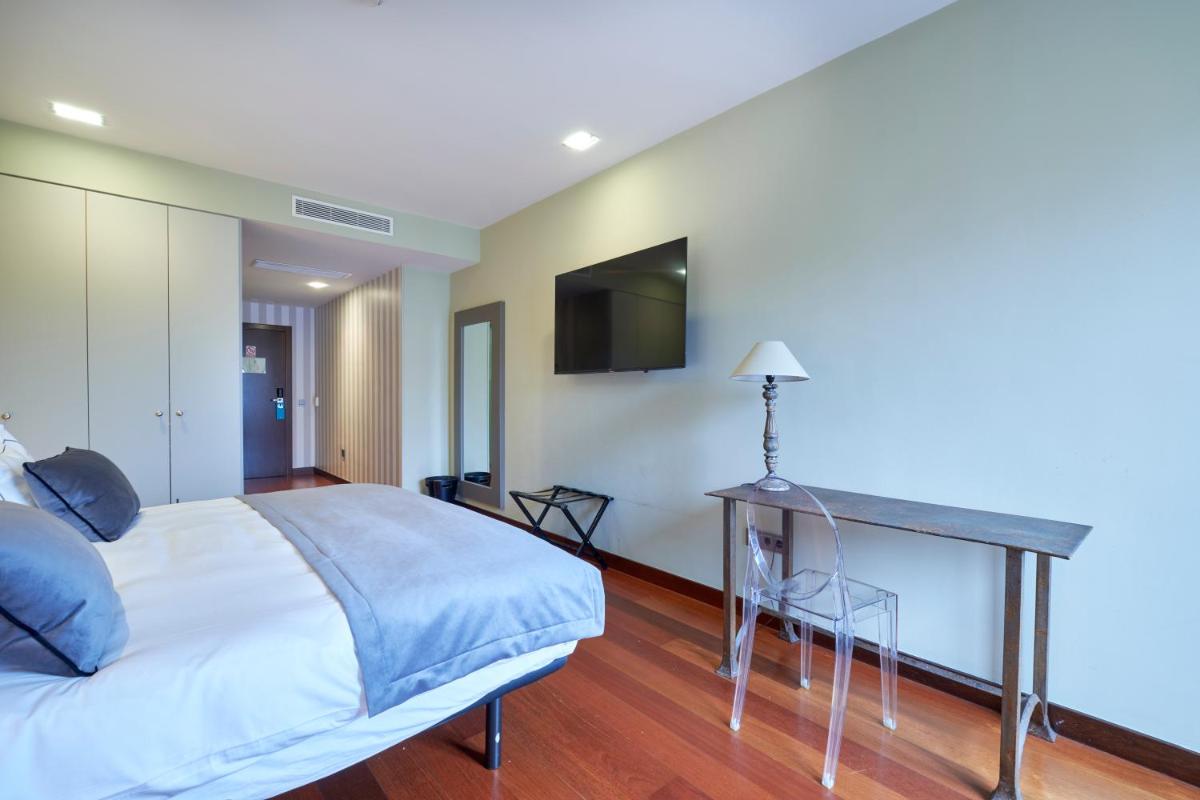 Un dormitorio con una cama y un televisor en la pared. en Hotel AR Isabel de Farnesio, en La Granja de San Ildefonso