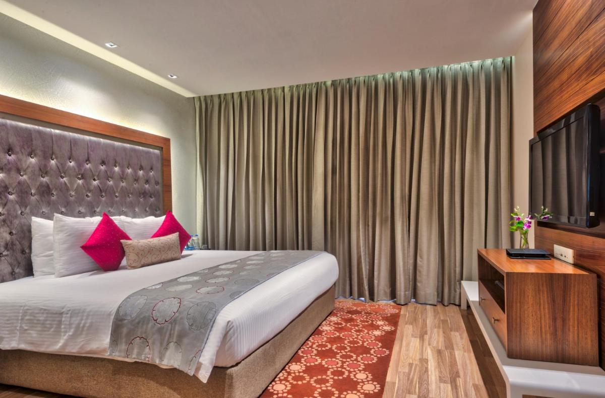 a bedroom with a large bed and a television at Grand Chennai by GRT Hotels in Chennai