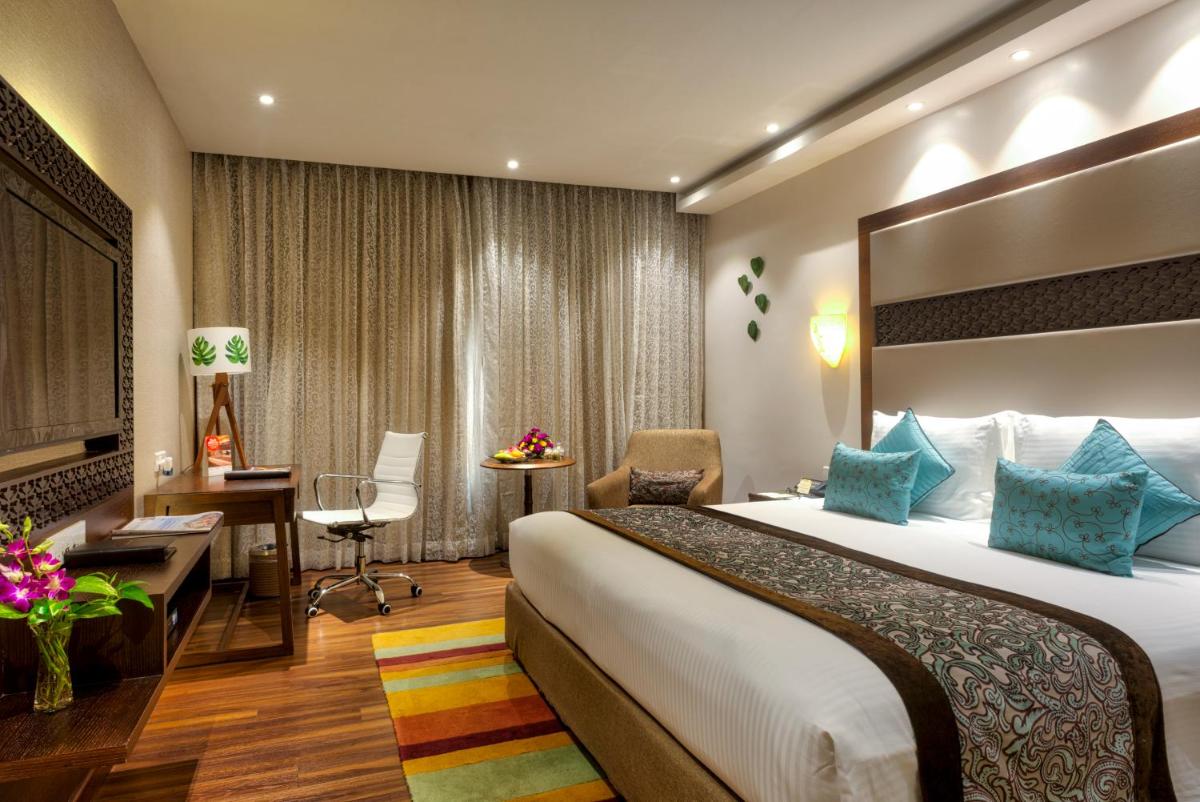 a hotel room with a large bed and a desk at Grand Chennai by GRT Hotels in Chennai
