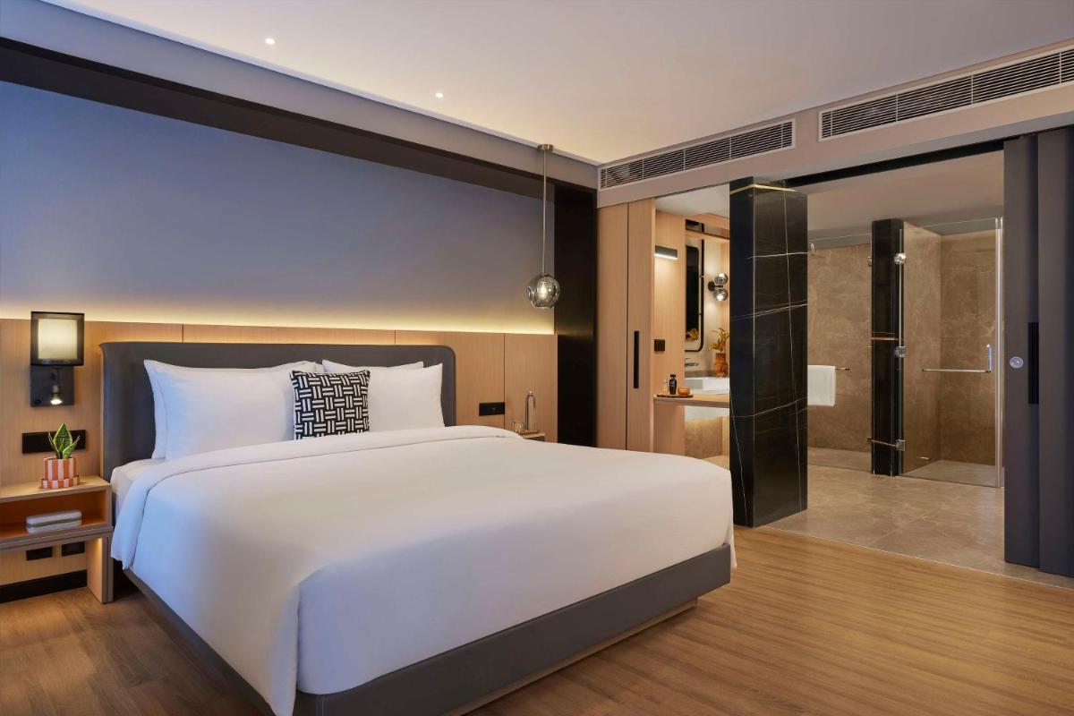 a bedroom with a large white bed and a bathroom at Hyatt Centric Hebbal Bengaluru in Bengaluru