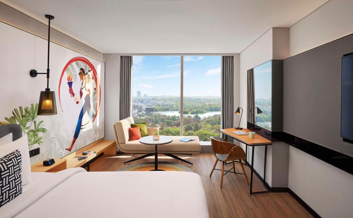 a bedroom with a bed and a living room with a view at Hyatt Centric Hebbal Bengaluru in Bengaluru
