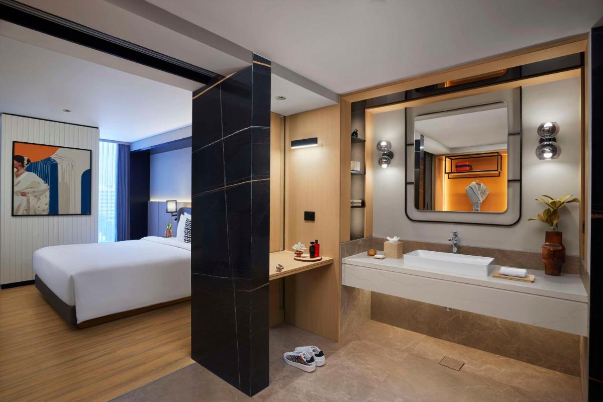 a bedroom with a bed and a bathroom with a sink at Hyatt Centric Hebbal Bengaluru in Bengaluru