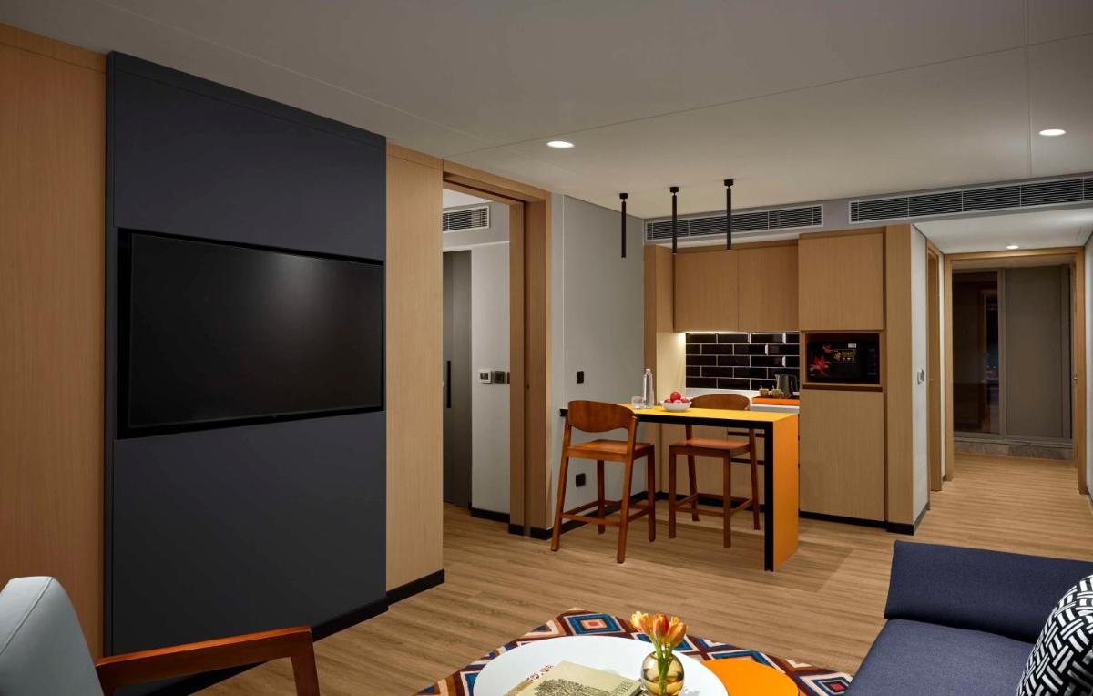 a living room and kitchen with a large flat screen tv at Hyatt Centric Hebbal Bengaluru in Bengaluru