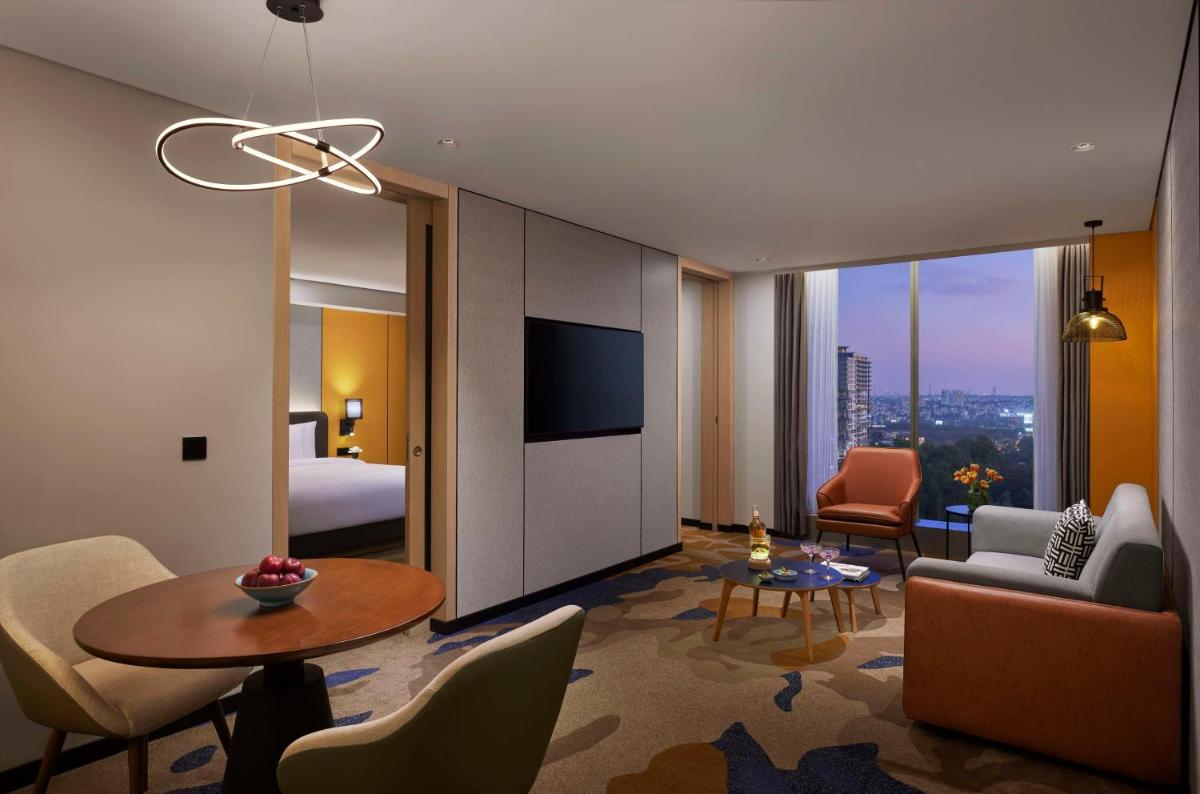 a hotel room with a bed and a living room at Hyatt Centric Hebbal Bengaluru in Bengaluru
