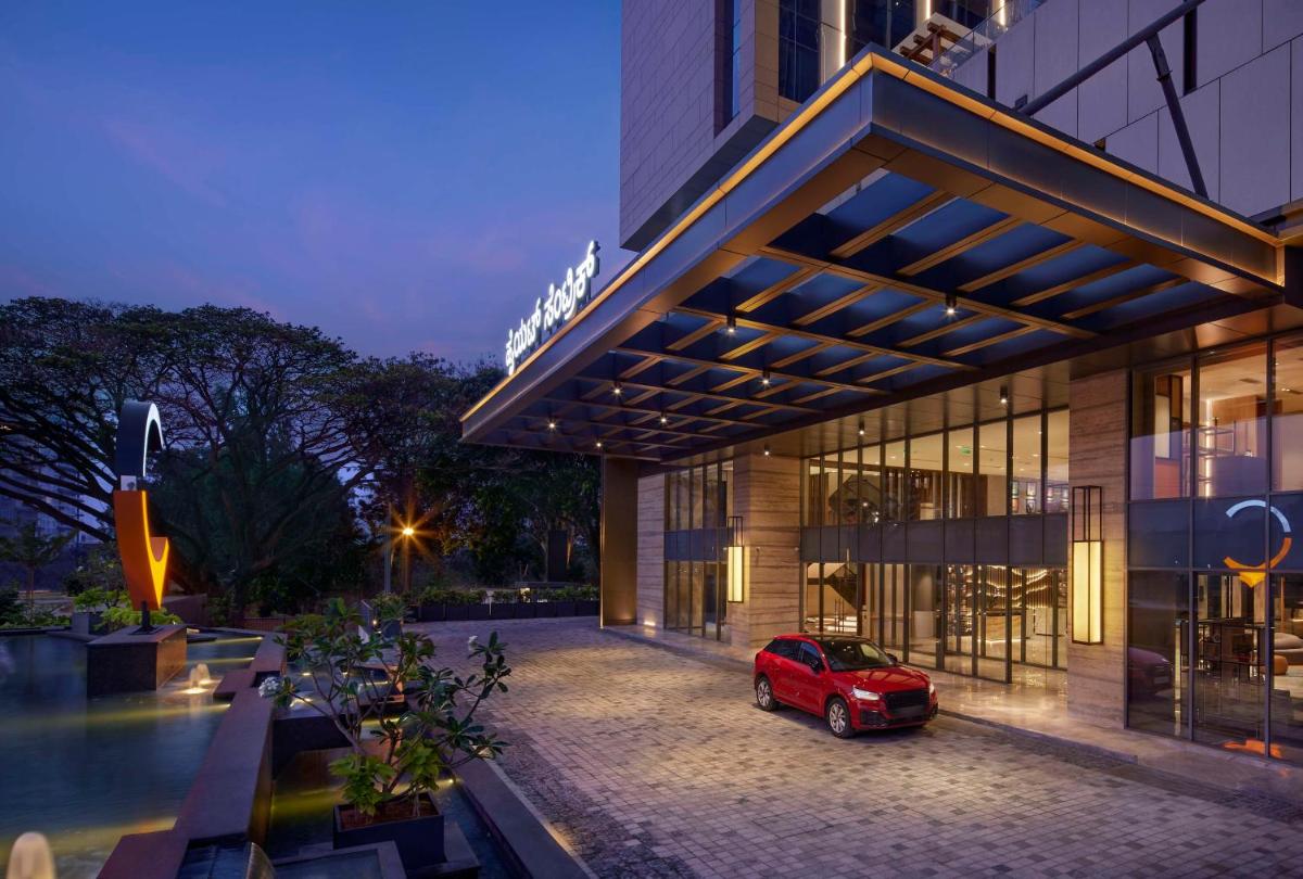 a red car parked in front of a building at Hyatt Centric Hebbal Bengaluru in Bengaluru
