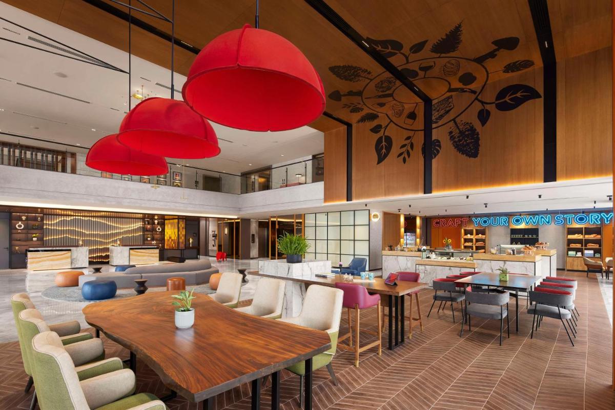 a lobby of a hotel with tables and chairs at Hyatt Centric Hebbal Bengaluru in Bengaluru