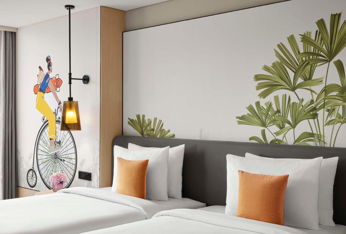 a bedroom with two beds and a poster of a woman on a bicycle at Hyatt Centric Hebbal Bengaluru in Bengaluru
