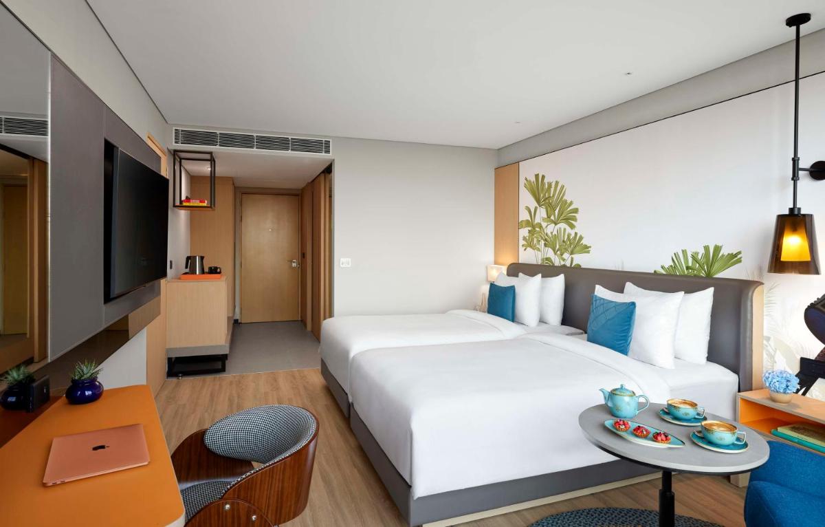 a hotel room with a large white bed and a table at Hyatt Centric Hebbal Bengaluru in Bengaluru
