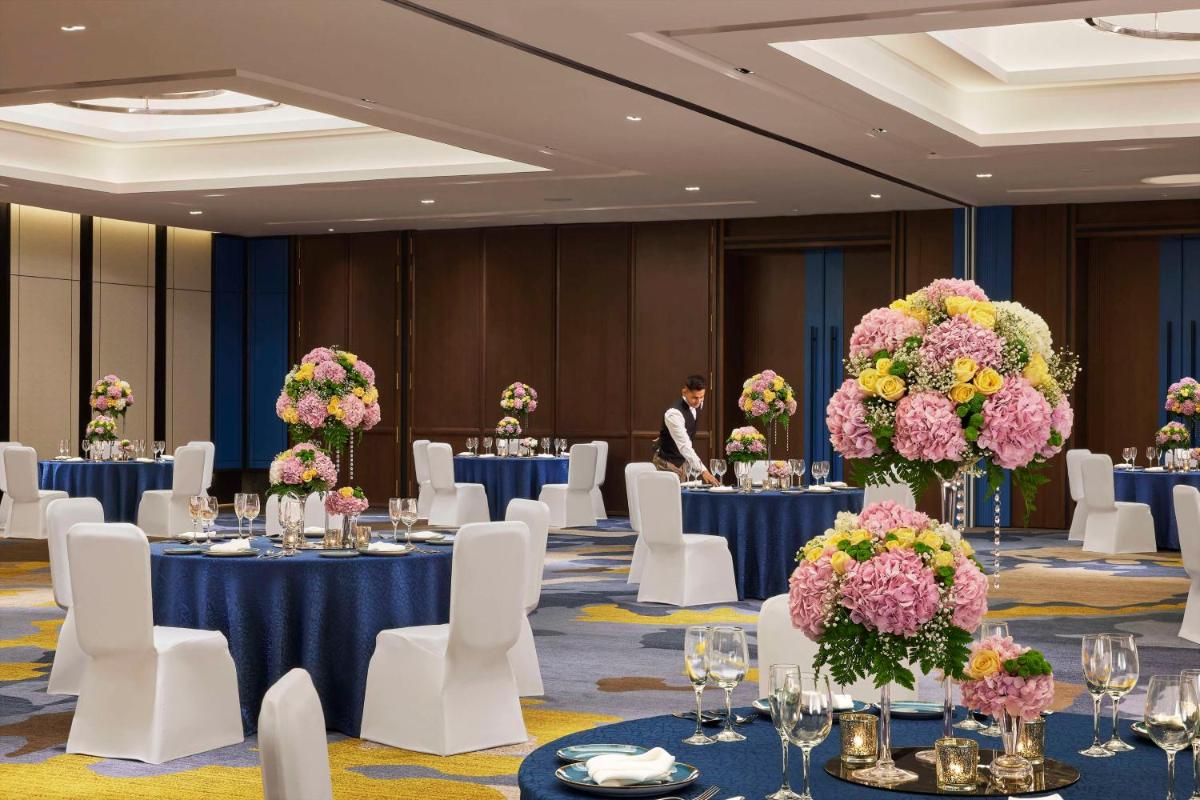 a ballroom with tables and chairs and a man in a suit at Hyatt Centric Hebbal Bengaluru in Bengaluru
