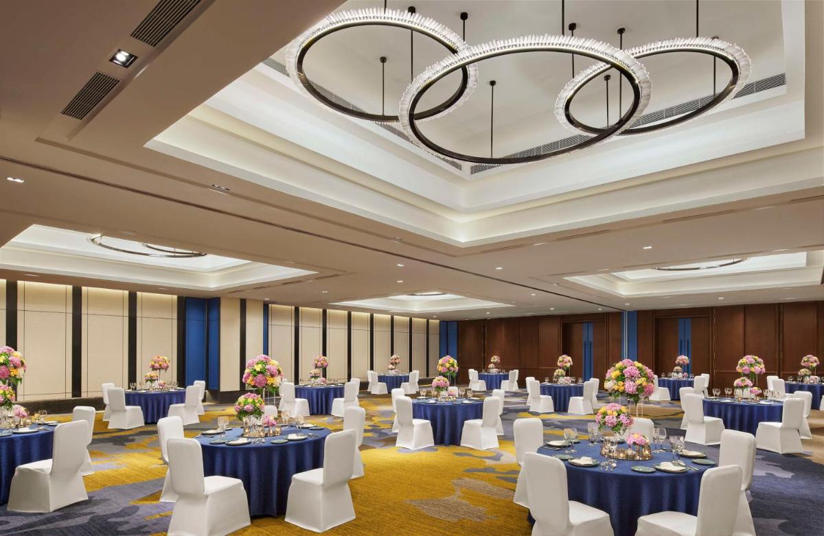 a ballroom with tables and chairs and a chandelier at Hyatt Centric Hebbal Bengaluru in Bengaluru