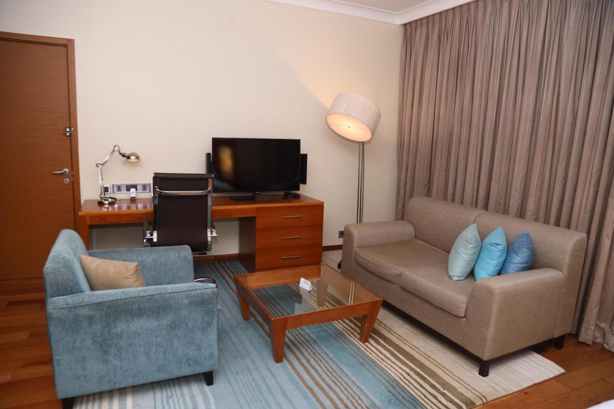 a living room with a couch and a chair and a tv at Hilton Bangalore Embassy GolfLinks in Bengaluru