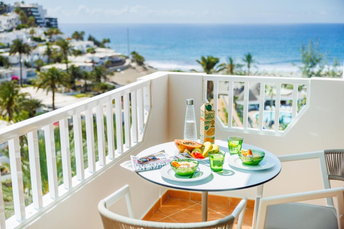 una mesa con comida en un balcón con vistas a la playa en Hapimag San Agustín, en San Agustín