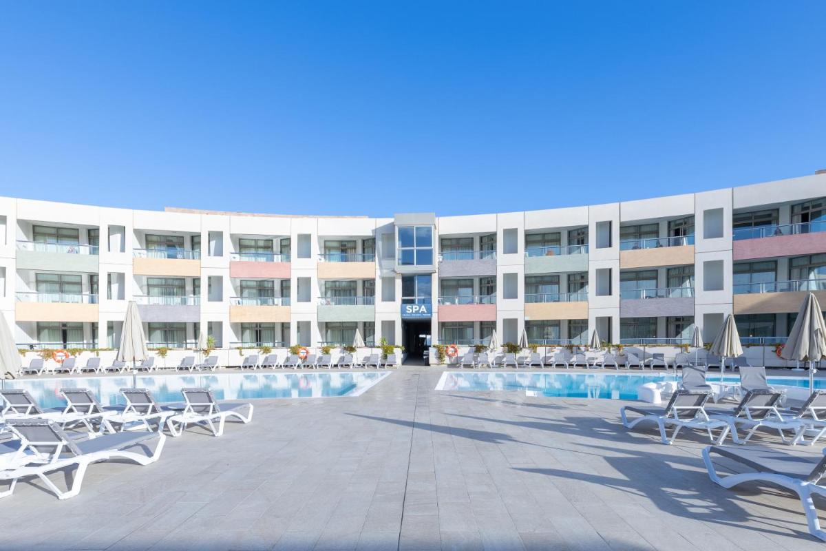 un hotel con sillas y una piscina frente a un edificio en Eurostars Las Salinas, en Caleta de Fuste