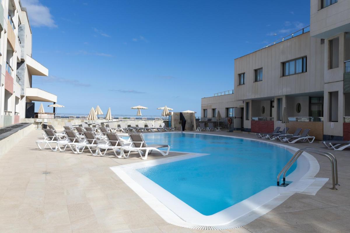 una gran piscina con tumbonas junto a un edificio en Eurostars Las Salinas, en Caleta de Fuste