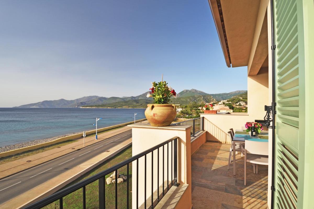 un balcon avec une table et une vue sur l'océan dans l'établissement Résidence Saint-Jean, à Saint-Florent