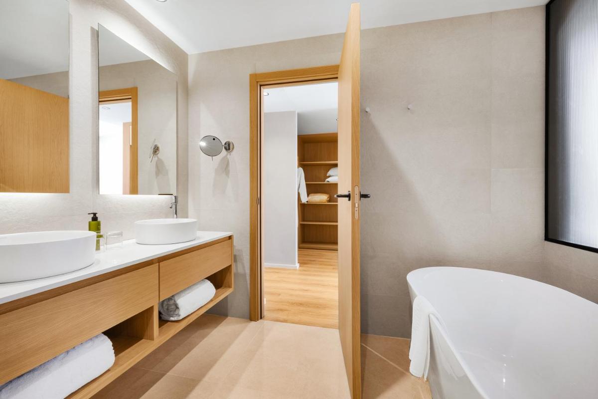 Un baño con dos lavabos, una bañera y un espejo. en Protur Sa Coma Playa Hotel & Spa, en Sa Coma