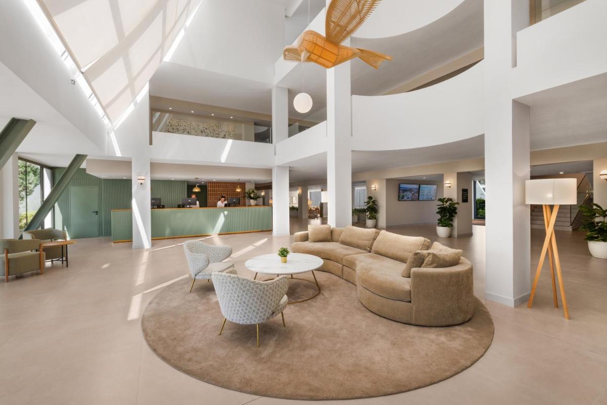 Un vestíbulo con un sofá, una mesa y sillas. en Protur Sa Coma Playa Hotel & Spa, en Sa Coma