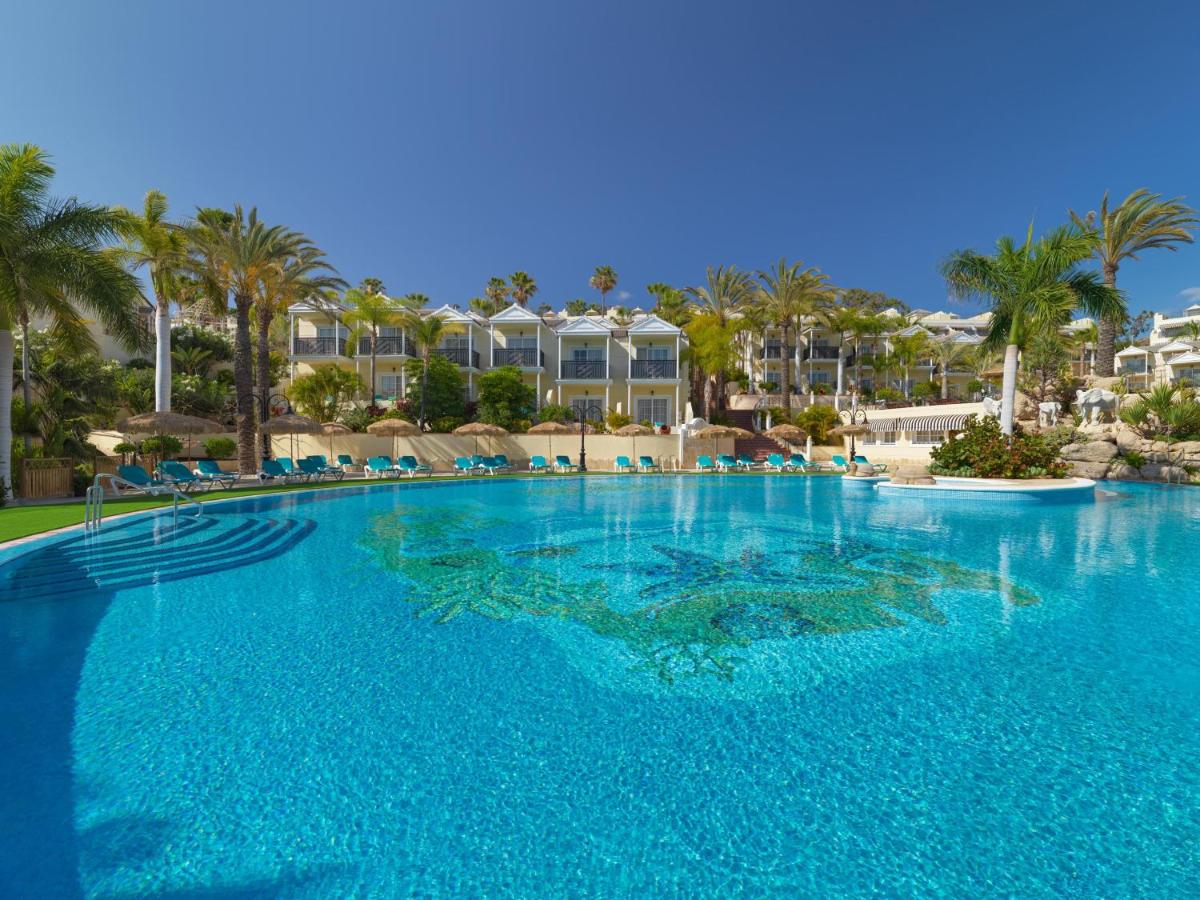 Una gran piscina con palmeras y edificios. en Gran Oasis Resort, en Playa de las Américas