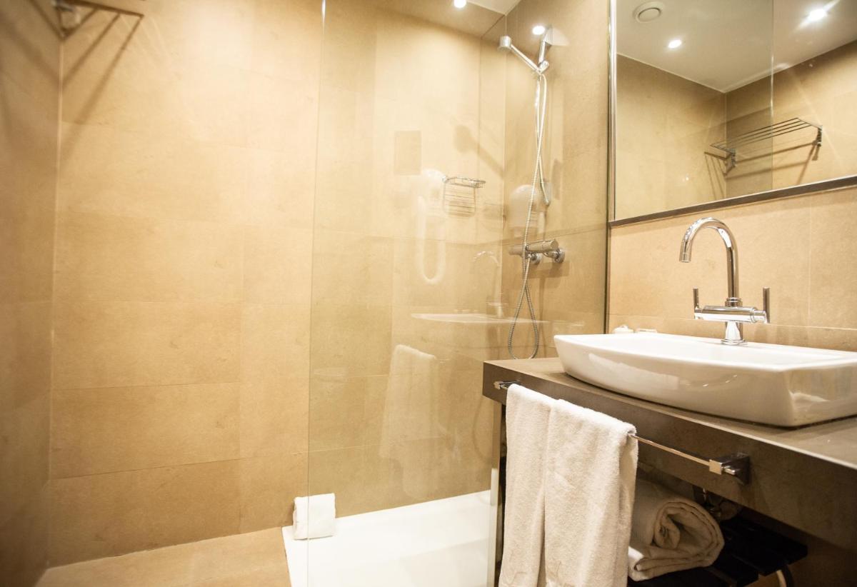 Un baño con lavabo y ducha de cristal. en AZZ Asturias LangreHotel & Spa, en Langreo