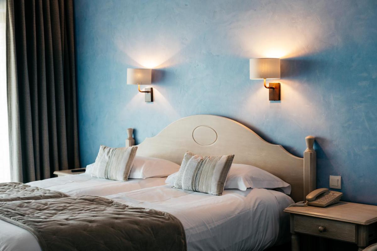 deux lits dans une chambre d'hôtel aux murs bleus dans l'établissement Hôtel Carcarille Restaurant Le C, à Gordes