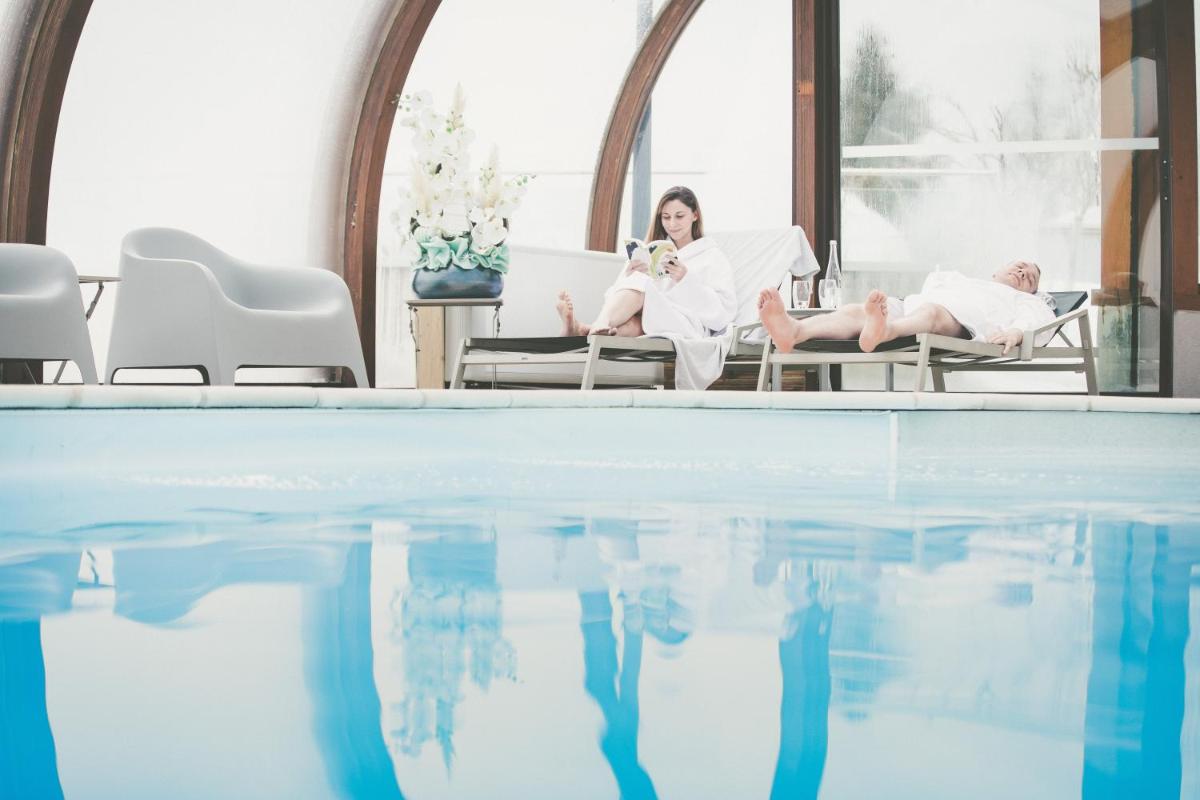 une femme assise sur des chaises à côté d'une piscine dans l'établissement Fleur De Neige Châtel, à Châtel