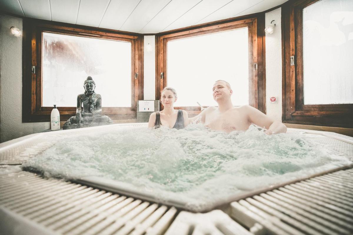 un homme et une femme assis dans une baignoire dans l'établissement Fleur De Neige Châtel, à Châtel