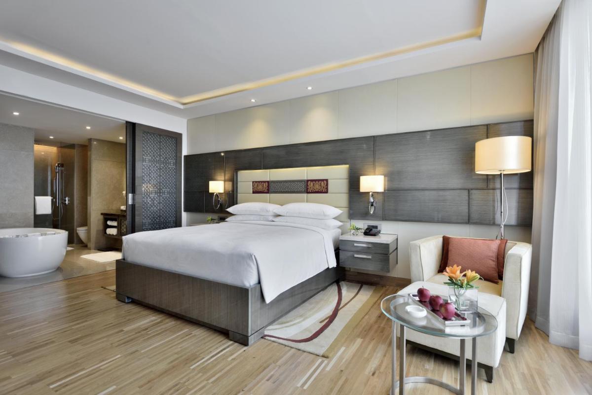 a bedroom with a large bed and a bath tub at JW Marriott Mumbai Sahar Airport in Mumbai a bedroom with a large bed and a bath tub at JW Marriott Mumbai Sahar Airport in Mumbai