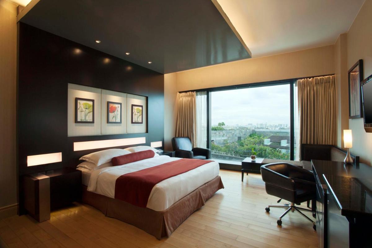 a hotel room with a bed and a desk and a window at The Oterra in Bengaluru