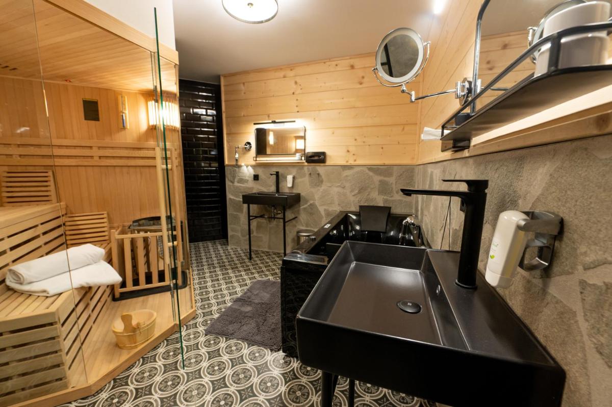 ein Bad mit einem schwarzen Waschbecken und einer Dusche in der Unterkunft ALPENLIEBE - Sauna & Whirlpool - APARTments in Inzell + 37 Fotos