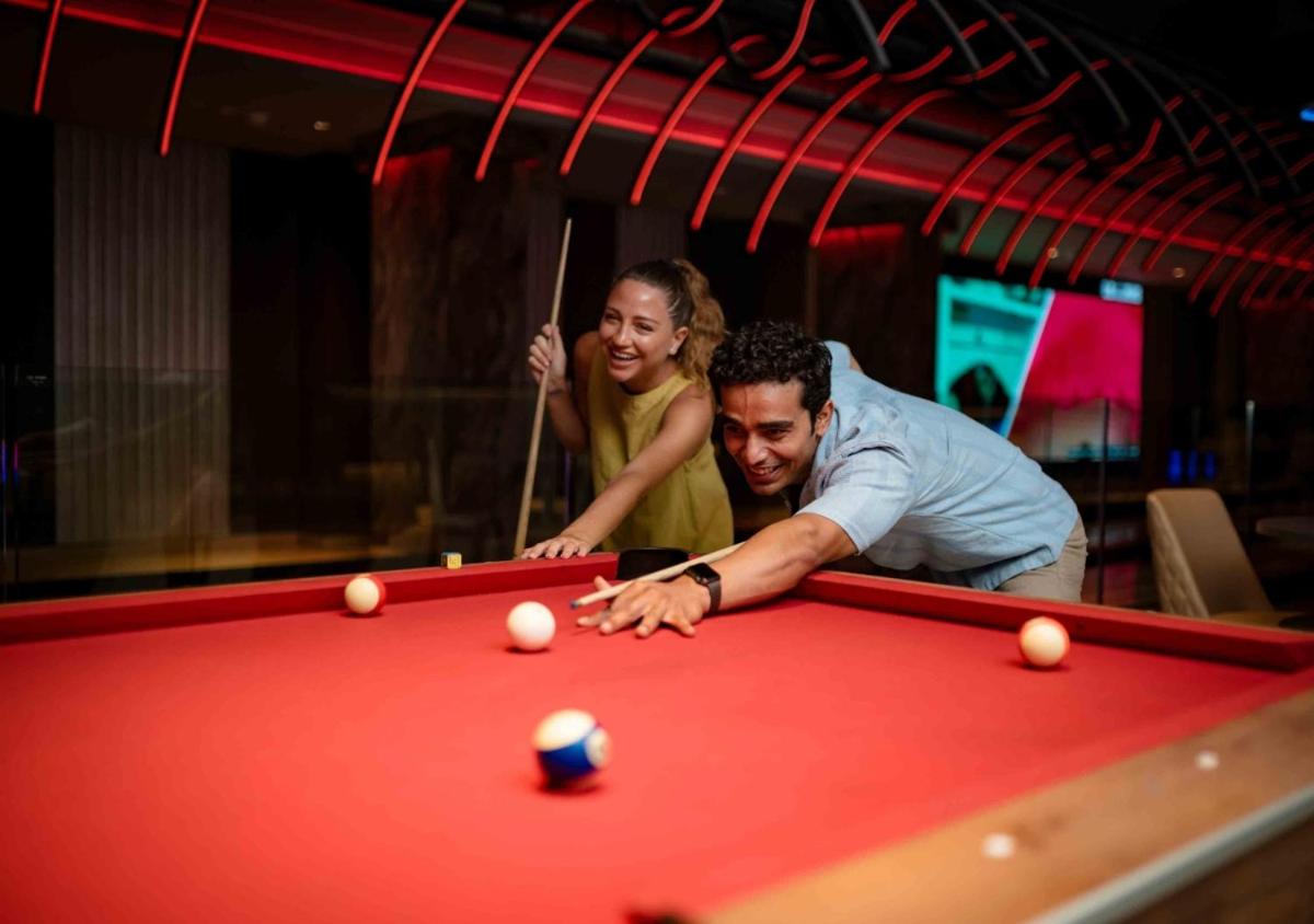 a man and a woman playing a game of pool at JW Marriott Goa in Vagator a man and a woman playing a game of pool at JW Marriott Goa in Vagator