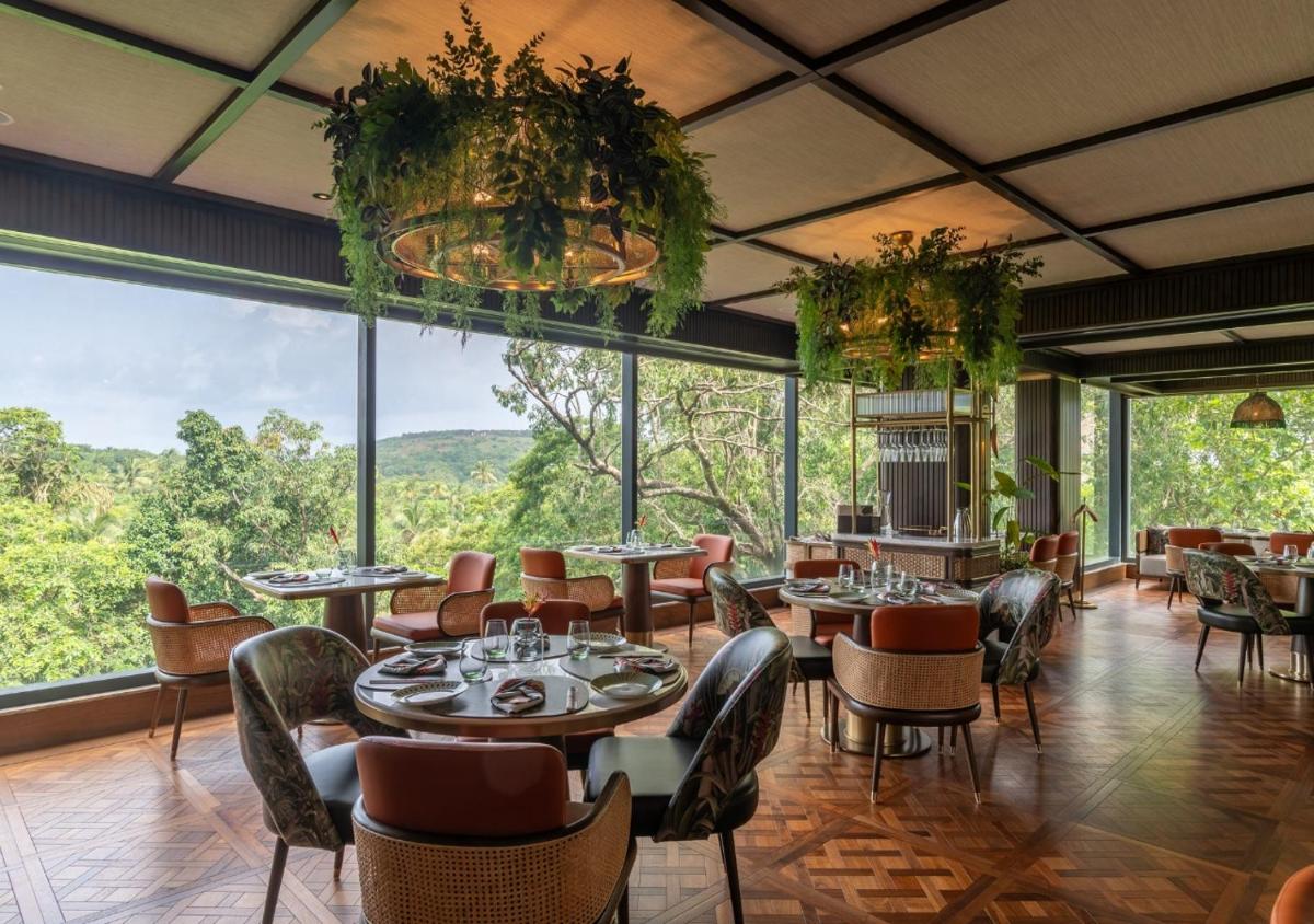 a restaurant with tables and chairs and large windows at JW Marriott Goa in Vagator a restaurant with tables and chairs and large windows at JW Marriott Goa in Vagator