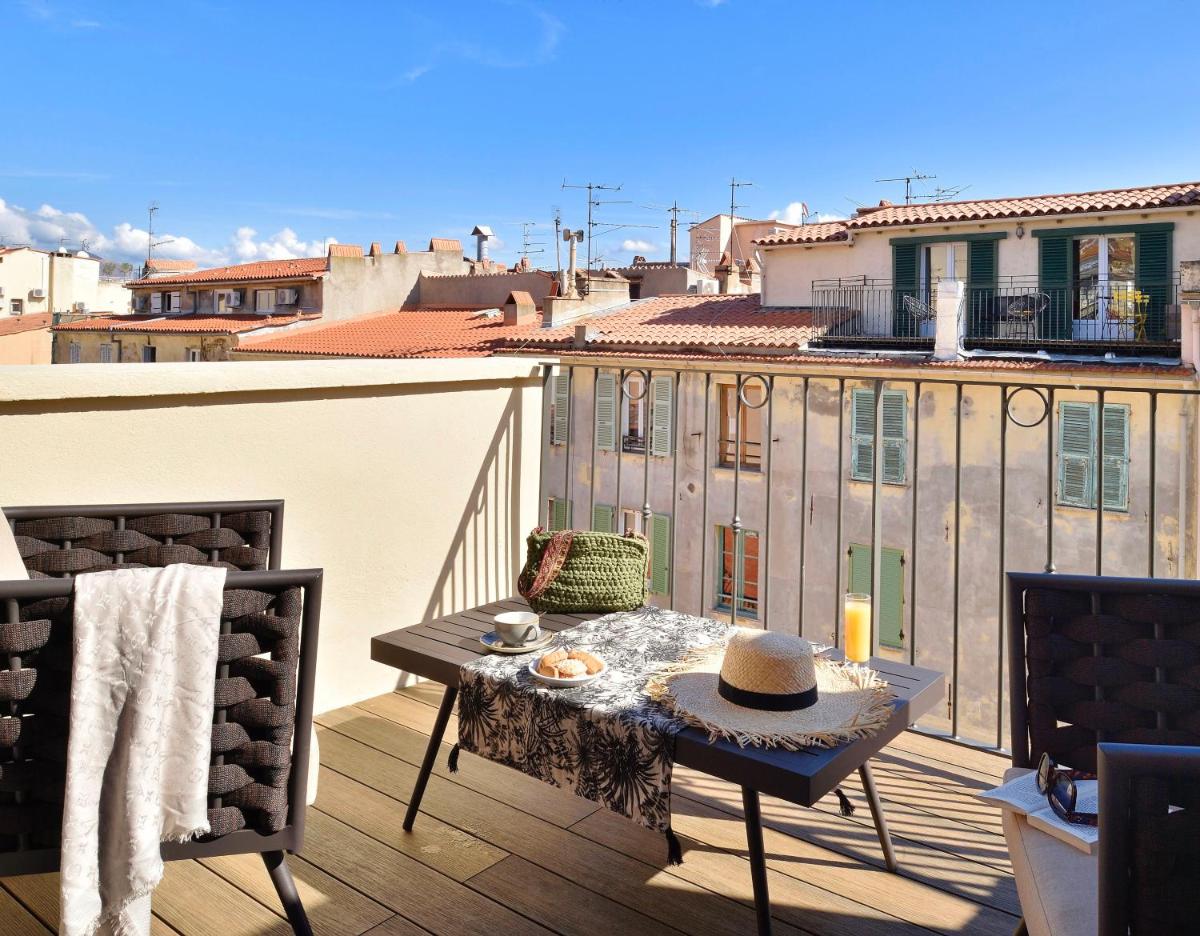 - un balcon avec une table et un chapeau dans l'établissement Hôtel Fesch & Spa, à Ajaccio
