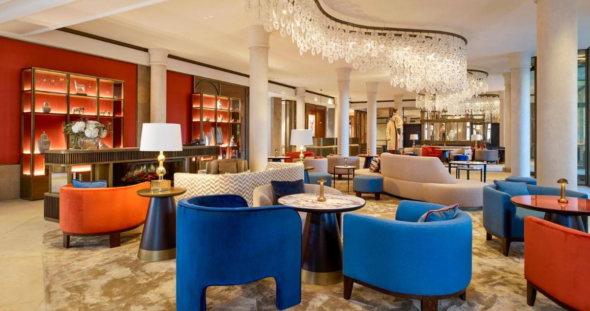 eine Lobby mit bunten Stühlen und Tischen sowie einem Kronleuchter in der Unterkunft Hotel Taschenbergpalais Kempinski in Dresden