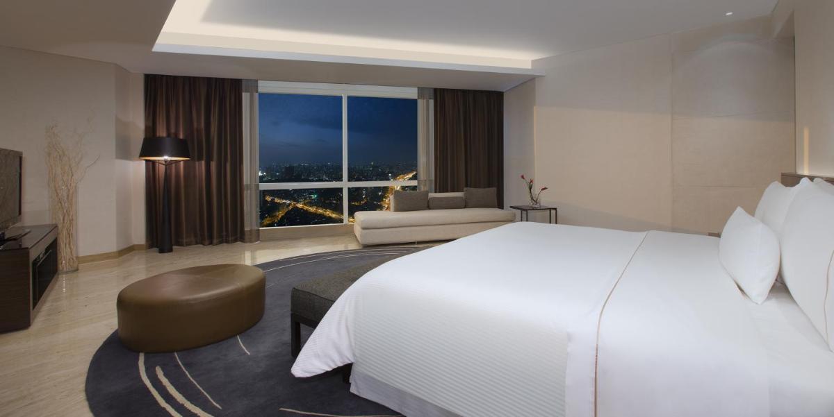a hotel room with a large bed and a large window at The Westin Mumbai Garden City in Mumbai