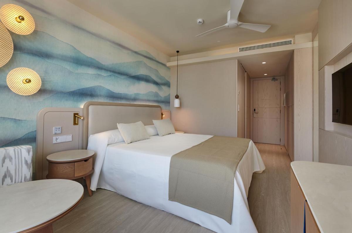 Un dormitorio con una gran cama blanca y una mesa. en Hipotels Flamenco, en Cala Millor
